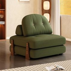 a green chair sitting on top of a floor next to a book shelf and window