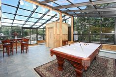 a pool table is in the middle of a room with glass walls and floor to ceiling windows