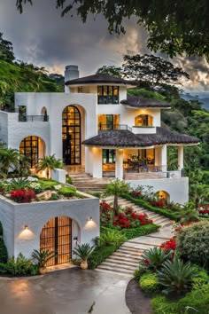 a large white house surrounded by trees and flowers