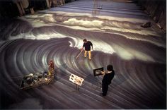 two people are standing in front of an enormous wave