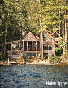 a large house sitting on top of a lake surrounded by trees