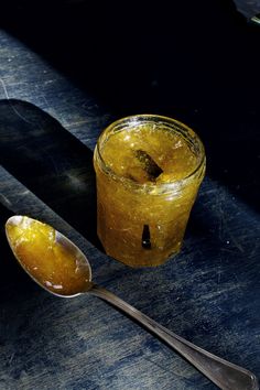 two spoons are sitting next to a glass with liquid in it on a table