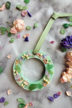 a green circle with flowers and leaves around it on a marble surface surrounded by confetti