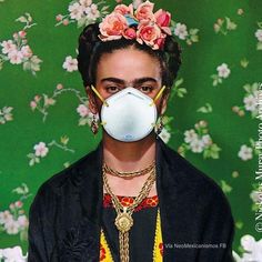 a woman wearing a mask with flowers on her head and necklaces around her neck