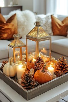 a tray filled with candles and pine cones on top of a coffee table next to a couch