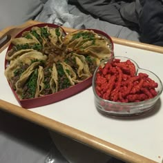 two heart shaped trays filled with food on top of a white table next to each other