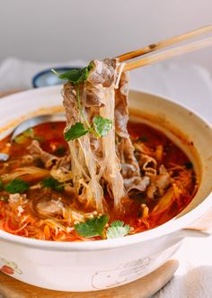 a white bowl filled with soup and chopsticks sticking out of the meat in it