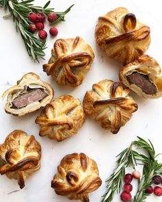 several pastries are arranged on a white surface next to berries and rosemary sprigs