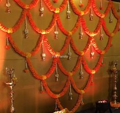 the wall is decorated with orange flowers and silver bells hanging from it's sides