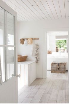 a kitchen with white walls and wood flooring next to an open door that leads to a bedroom