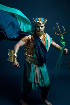 a man dressed in costume holding a flag and wearing a horned headdress while standing against a dark background