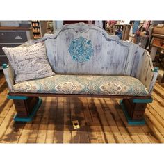 an old wooden bench with blue and white fabric on it's back, in a store