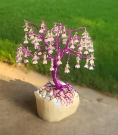 a small purple tree sitting on top of a rock