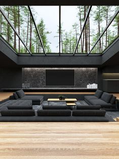 a living room with black couches and tables in the center, surrounded by tall trees