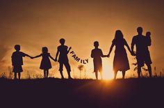 silhouettes of people holding hands with the sun setting in the sky behind them,