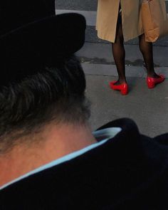 a woman in red shoes is standing on the street