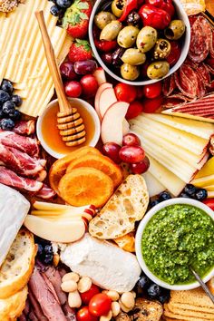 an assortment of cheeses, meats and fruit on a platter with bread sticks