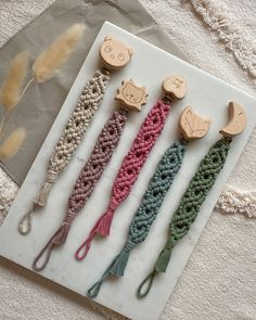 four crocheted hair clips are laying on a piece of paper next to some feathers