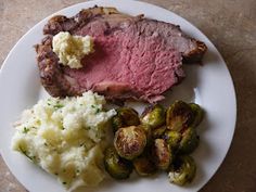 a white plate topped with meat, mashed potatoes and brussel sprouts