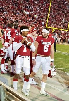 the football team is standing on the sidelines at the stadium and talking to each other