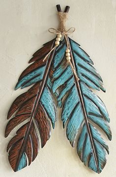 a blue and brown leaf hanging on a wall next to a white wall with a rope