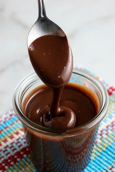 chocolate sauce being poured into a jar with the words easy homemade recipe for hot fudge sauce