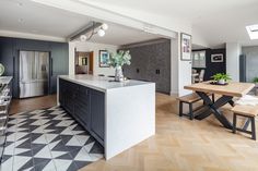 an open kitchen and dining room area with black cabinets, checkered flooring and white counter tops