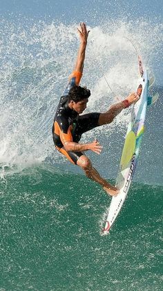 a man riding a surfboard on top of a wave in the ocean with his arms out