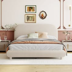 a bedroom with pink walls, white bedding and pictures on the wall above it