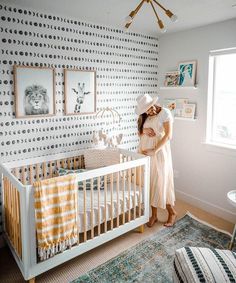 a woman standing next to a baby crib in a room with polka dot wallpaper