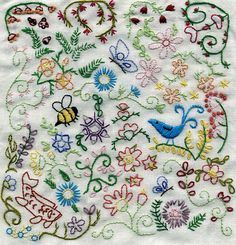 an embroidered square with flowers, birds and butterflies on white linens that have been stitched together