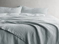 an unmade bed with white sheets and pillows