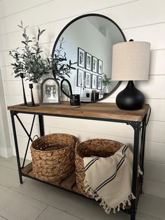 a table with two baskets and a mirror on top of it next to a lamp