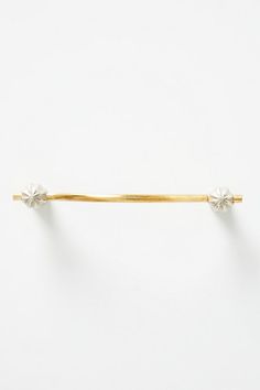 a gold tie bar with two small white flowers on the end, and one yellow pin