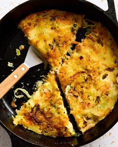 an omelet is being cooked in a skillet with a spatula on the side