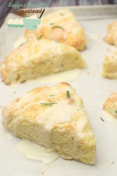 scones with white sauce and green herbs on them are sitting on a baking sheet