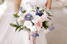 a bride holding a bouquet of white and blue flowers