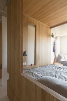 a person walking past a bed in a room with wood paneling on the walls