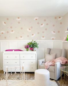 a baby's room is decorated with pink and white flowers on the wall, along with a crib