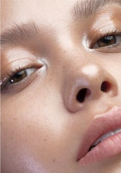 a close up of a woman with makeup on her face and eyeliners in the background