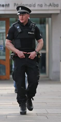 a police officer is walking down the street with his hands in his pockets while wearing all black