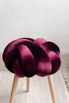 a purple chair sitting on top of a white rug next to a wooden leg stool