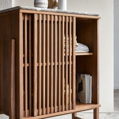 a wooden cabinet with books and vases on top