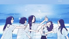 four girls are standing in front of the ocean and one girl is holding something up to her head