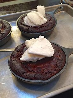 three chocolate cupcakes with whipped cream on top are sitting in a baking pan