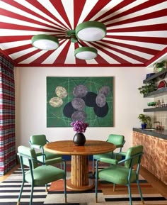 a dining room table with green chairs under a red and white striped ceiling