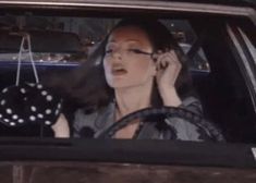 a woman talking on her cell phone while sitting in the driver's seat of a car