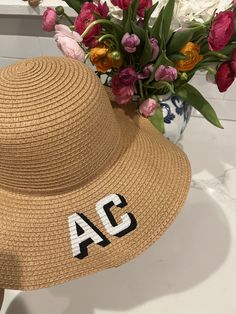 a tan hat with the letters ac on it next to a bouquet of flowers in a vase