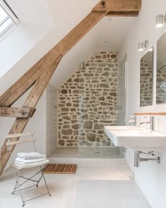 an attic bathroom with stone walls and exposed wood beams, along with a walk in shower