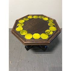 a wooden table with yellow flowers painted on the top and wheels in front of it